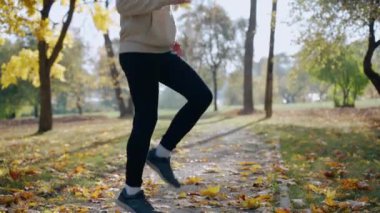 Adam sonbaharda parkta sabah koşusundan önce egzersiz yapıyor ve esniyor.