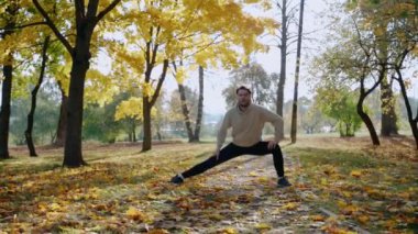 Adam sonbaharda parkta sabah koşusundan önce egzersiz yapıyor ve esniyor.