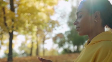 Güneşli bir sonbahar sabahı parkta koşmadan önce su içen genç bir kız.