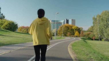 Güneşli bir sonbahar sabahında şehir parkında koşan genç bir kız.