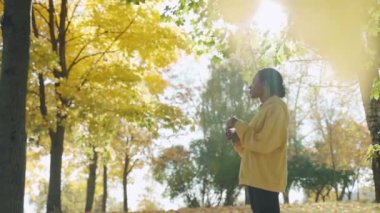 Güneşli bir sonbahar sabahı parkta koşmadan önce su içen genç bir kız.