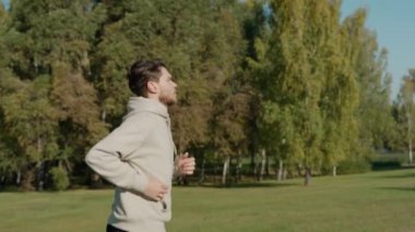 Güneşli bir sonbahar sabahında, şehir parkında koşan bir adam.