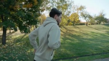 Güneşli bir sonbahar sabahında, şehir parkında koşan bir adam.