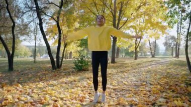 Kız sonbaharda parkta sabah koşusundan önce kriko ve esneme hareketleri yapıyor.
