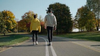 Kadın ve erkek sonbaharda parkta koşmaya başlar, konuşur ve gülümserler.