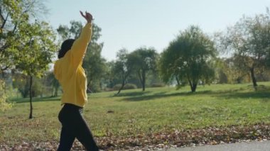 Sonbaharda şehir parkında koştuktan sonra nefes egzersizi yapan bir kız. 