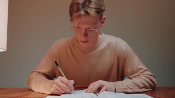 Encerramento do jovem estudando em casa escrevendo em suas anotações, lendo um livro — Vídeo de Stock