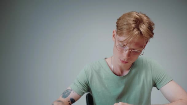 Homem de óculos estudando e estressante, lendo um livro didático em quarto cinza vazio — Vídeo de Stock