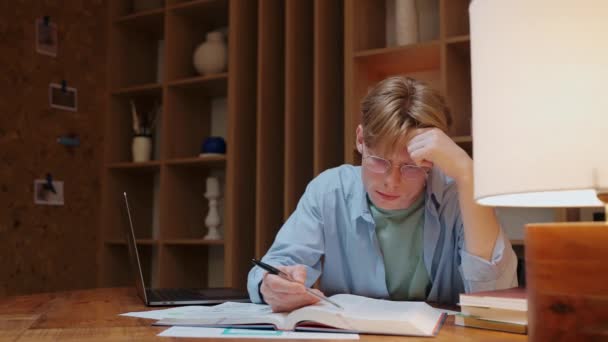 Fiatal férfi szemüvegben tanul és stresszel a meleg fa szobában — Stock videók