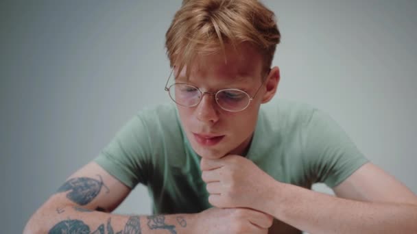 Young man in glasses reading a textbook and stressing, with his fist in his chin — Stock Video