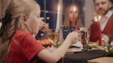 Noel arifesinde yemek masasında kırmızı giyinmiş küçük bir kız.