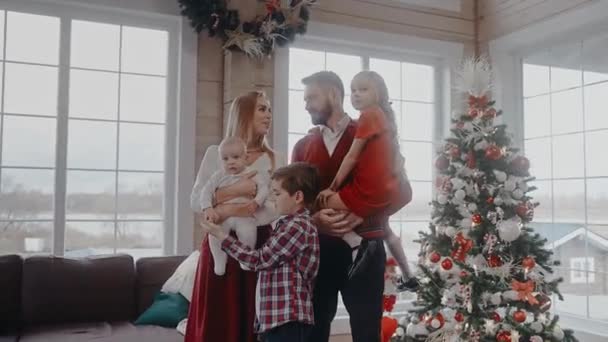 Família com crianças vestidas para a véspera de Natal na frente da árvore, olhe para a câmera — Vídeo de Stock