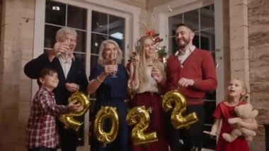 Mutlu aile 2022 yılını kutluyor, gülüyor ve cınlayan gözlüklere sarılıyor.