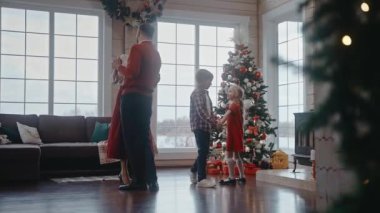 Ebeveynler birlikte dans ediyor ve çocuklar da arkada, Noel atmosferinde.