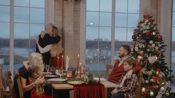 圣诞前夕，祖父母和孩子们在喜庆的餐桌旁拥抱 — 图库视频影像