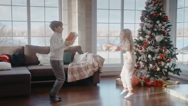 Chlapec a dívka jsou šťastně skákání s dárky na Vánoce ráno — Stock video