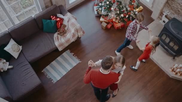 Děti přicházející obejmout rodiče tancující u vánočního stromečku, pohled shora — Stock video