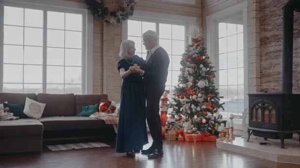 Nagyszülők táncolnak együtt a karácsonyi partin közel a kandallóhoz és a fához — Stock videók