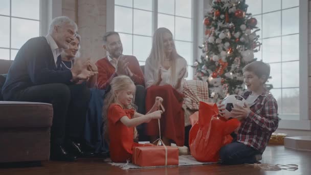 Děti dostávají míč a medvídka jako dárek k Vánocům, rodinná oslava — Stock video