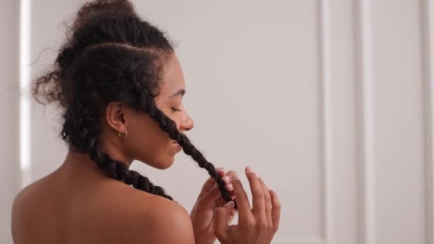 Черная молодая женщина скручивает волосы после ванны в белой комнате и смотрит в камеру — стоковое видео