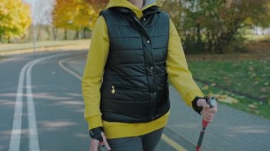 Güneşli sonbahar parkında tek başına yürüyen yaşlı bir kadın. 