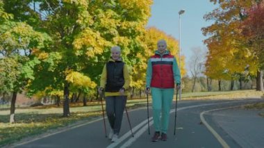 Yaşı büyük kadınlar sağlıklarına dikkat etmek için sonbahar parkında, ön cephede yürürler. 