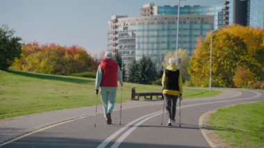 Güneşli bir günde, arka planda Nordic yürüyüşü yapan iki yaşlı kadın 