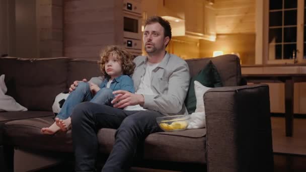 Junge sitzt mit seinem Vater beim Sport und freut sich über das erzielte Tor — Stockvideo