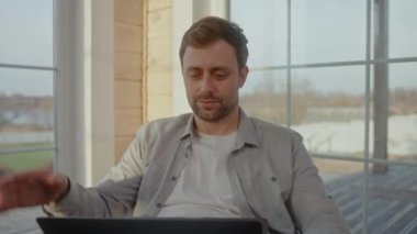 Bilgisayarda video görüşmesi yapan bir adam, evde kilit altında çalışıyor.