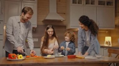 Aile evde akşam yemeği için pizza pişiriyor, çocuklarla gülüyor ve dans ediyor.