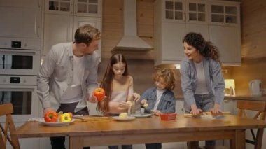 Aileler evde yemek pişirirken çocuklar onlara yardım ediyor. 