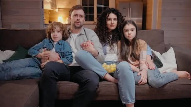 Rodzina ogląda razem film w domu przytulając się, przerażona horrorem — Wideo stockowe