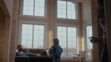 Çocuklar laptopun başında çalışırken annelerine koşup ona kanepede sarılıyorlar.