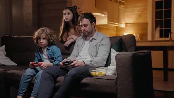 Отец играет со своим сыном в игровой приставке, смеется и дерется на диване — стоковое видео