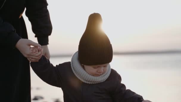 Junge spaziert mit seiner Mutter am Steinufer und winkt an einem Herbstabend — Stockvideo