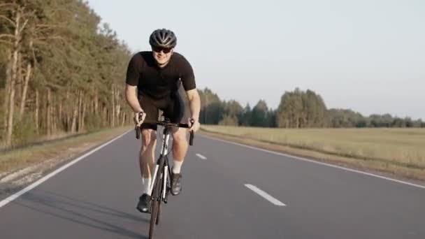 Muž uhánějící na silničním kole na dálnici při západu slunce, v helmě — Stock video