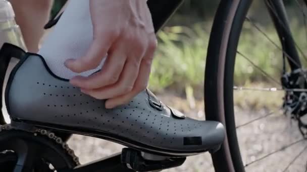 Homem torce os sapatos de bicicleta de contato em uma bicicleta de estrada ao pôr do sol na floresta — Vídeo de Stock