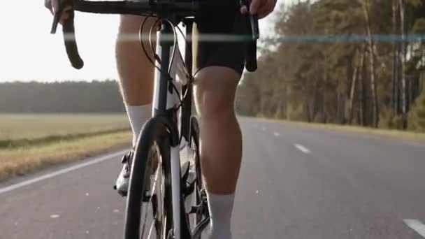 Primo piano dell'uomo che guida una bici da strada al tramonto su un'autostrada, indossando il casco — Video Stock