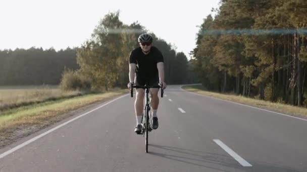 Zdjęcie mężczyzny jadącego na rowerze o zachodzie słońca na autostradzie w kasku. — Wideo stockowe