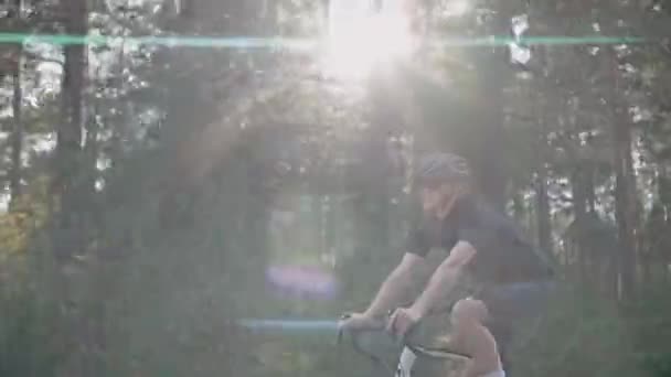 Бічний знімок велосипедиста, який їде на шоломі в сонячному лісі — стокове відео