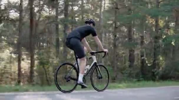 Foto lateral de ciclista andando de bicicleta em uma floresta ensolarada, usando capacete — Vídeo de Stock