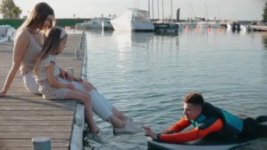 Kızı olan bir kadın gün batımında babasıyla sörf tahtasında oturup konuşur.