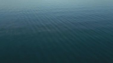 Büyük mavi bir gölün üzerinde pembe bir günbatımında sinematik kamera uçuşu