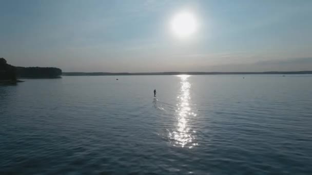 Άνθρωπος ιππασία σε μια σανίδα του σερφ υδροφύλλου σε μεγάλη μπλε λίμνη σε ηλιόλουστο καιρό — Αρχείο Βίντεο