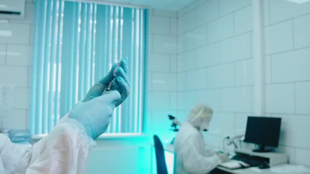 Медик у захисному костюмі вставляє шприц у ампулу з ліками — стокове відео