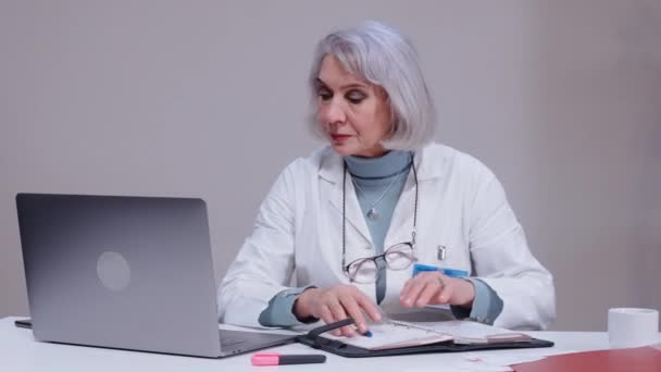Γυναίκα γιατρός μιλάει με ασθενή σε βίντεο chat στο φορητό υπολογιστή στο λευκό γραφείο — Αρχείο Βίντεο