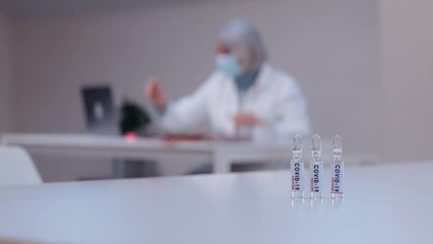 Médico trabajador agarra ampollas con covid-19 en el fondo de trabajo médico — Vídeos de Stock