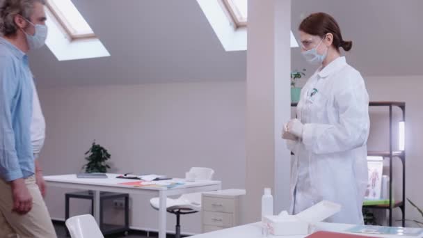 Menina vacina um homem contra coronavírus em uma clínica privada brilhante — Vídeo de Stock