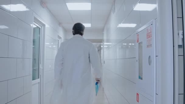 Dokter loopt uit de rode zone van covid-19, het dragen van medische jurk en masker — Stockvideo
