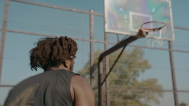 Svart man tåg gör smäll dunk ensam på en gata basketplan — Stockvideo